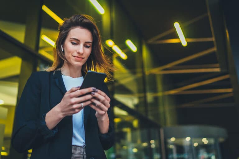 Successful female banker using smartphone outdoors